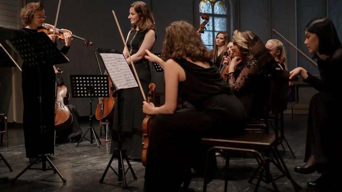 Female musicians rehearsing for event retreat in dimly lit room.