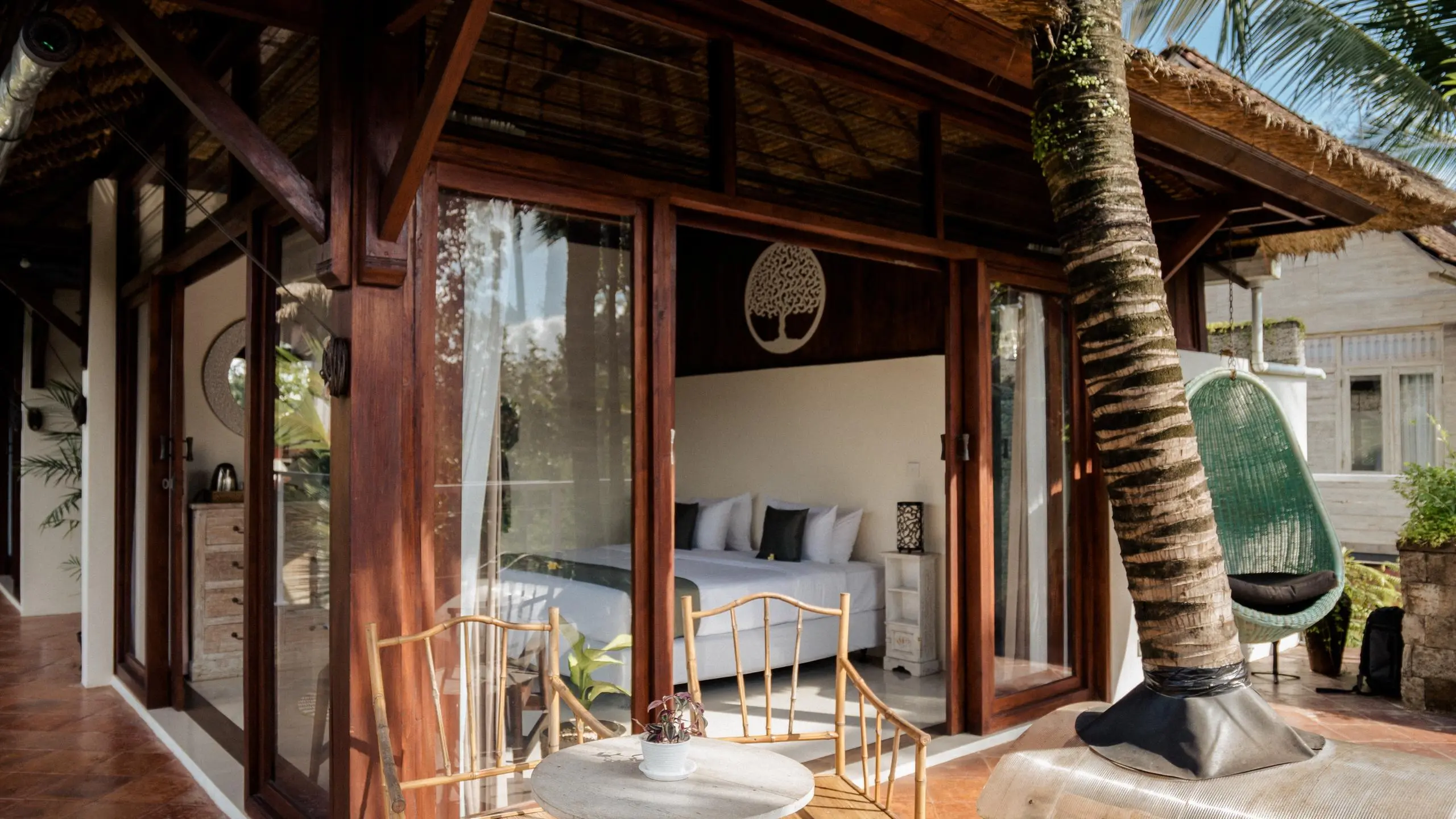 Outdoor patio with table and chairs under palm tree at a sustainable retreat