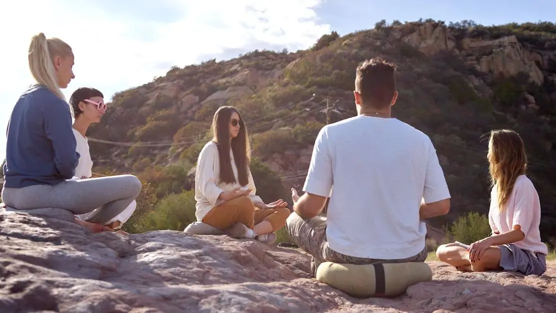 Adults meditating outdoors, representing the eight limbs of yoga and mindful practice.