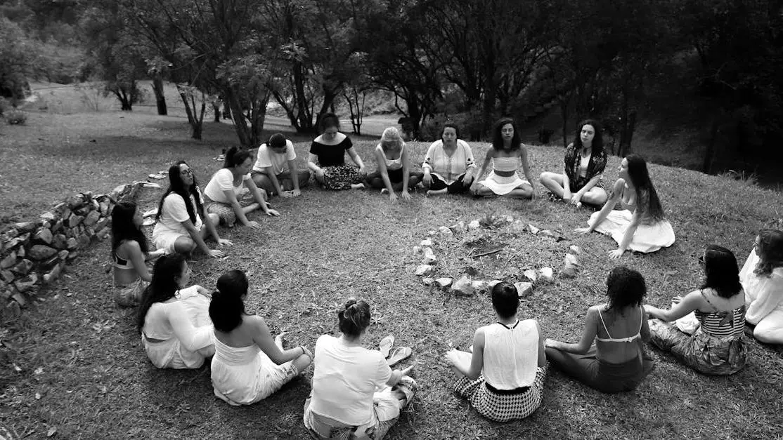 Diverse group meditating outdoors in a circle, illustrating group meditation benefits.