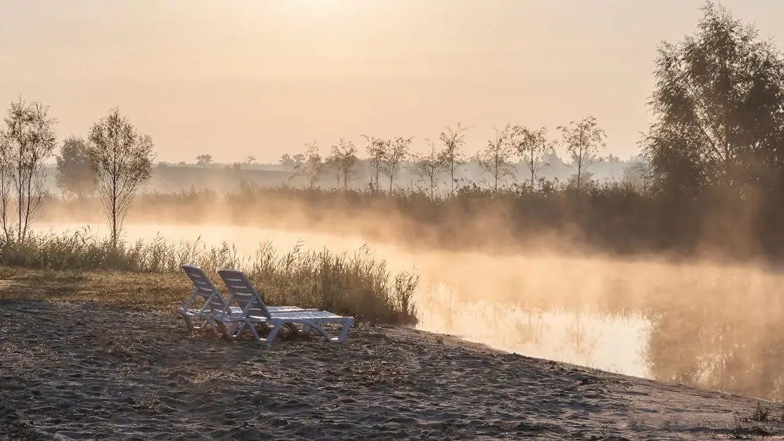 Misty sunrise over Ubud riverbank with lounge chairs and serene waters, hidden gems Ubud